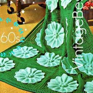 Puede incluir: Una manta de ganchillo vintage con fondo verde y diseños de flores azul claro. La manta está hecha con un patrón de cuadrados de la abuela y tiene un ambiente de los años 60.