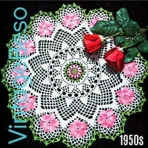 Könnte beinhalten: Eine weiße Häkeldeckchen mit grünem Rand und rosa Blüten. Das Deckchen ist von zwei roten Rosen mit grünen Blättern umgeben. Der Text "1950s" befindet sich in der unteren rechten Ecke des Bildes.