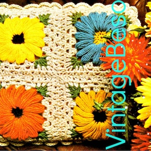 May include: A crocheted pillow with four large, colorful flowers. The flowers are yellow, orange, and blue, with green leaves. The pillow has a cream-colored background and a scalloped edge. The word "Vintage" is written vertically on the right side.