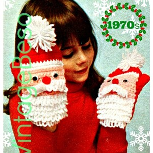 May include: A vintage image shows a young person holding two red and white crocheted Santa Claus mittens. The mittens have black eyes, a red nose, and a white beard. The image has the text "Vintage Besos" and "1970s".