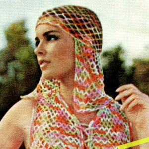 May include: A woman wearing a colorful crocheted top and matching hat. The top and hat are made with a variety of colors, including pink, orange, green, and white.