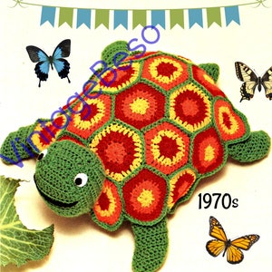 May include: A crocheted turtle toy with a green body and a colorful shell made of red, yellow, and orange hexagons. The turtle has a smiling face with black eyes and a green mouth. The toy is surrounded by butterflies and a banner with the text "1970s".