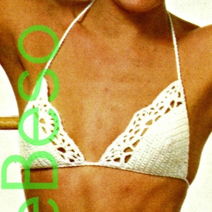 May include: White crochet bikini top with a delicate, lacy design. The top has a triangular shape and adjustable straps.
