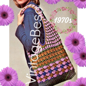 May include: A woman is holding a crocheted tote bag with a brown, green, blue, and purple color scheme. The bag has a large, open top and a single strap. The bag is labeled "Vintage Beso 1970s".