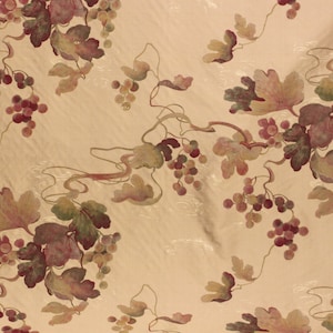 May include: A beige fabric with an embroidered pattern of grape vines with green and purple leaves and grapes.