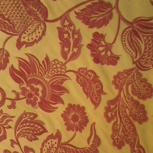 Könnte beinhalten: Ein gelber Stoff mit einem roten Blumenmuster. Das Muster zeigt stilisierte Blumen, Blätter und Ranken.