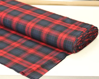 May include: Red and navy blue plaid fabric rolled up. The fabric has a woven texture.
