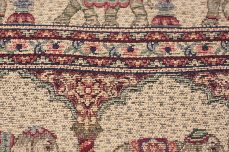 May include: Close-up of a beige rug with a detailed floral pattern in shades of red, blue, and green. The rug has a woven texture and intricate details.