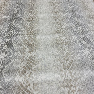 May include: A close-up of a rug with a snakeskin pattern in shades of gray, brown, and white.
