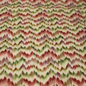 Op de afbeelding: Een stof met een chevron-patroon in tinten rood, groen, paars en wit.