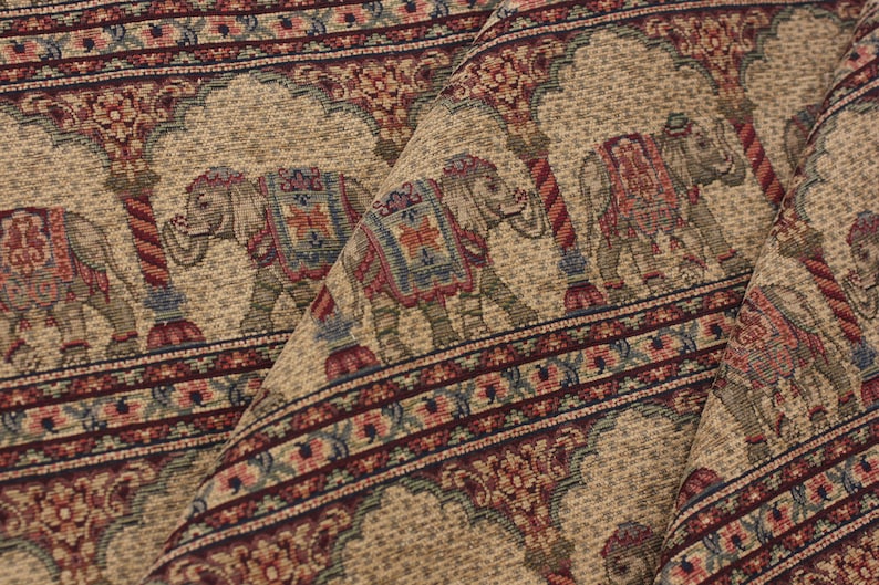 May include: Beige fabric with a repeating pattern of elephants and floral designs in shades of red, blue, and green.