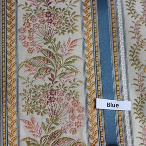 May include: Textile with a repeating pattern of vertical stripes in blue, gold, and cream. Floral and leaf motifs are interspersed between the stripes. The word "Blue" is on a white label.