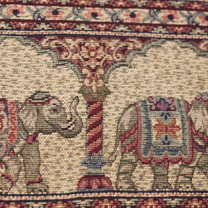 May include: A beige tapestry featuring a repeating pattern of elephants and floral designs. The elephants are carrying colourful saddle blankets and are walking under a stylised tree.