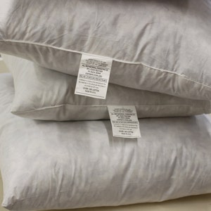 Puede incluir: Tres almohadas blancas apiladas una encima de la otra. La almohada superior tiene una etiqueta blanca con texto negro que dice "All Natural Down Comforter, 100% Duck Down, Fill Weight 20 oz, 100% Cotton Shell, Made in USA". La almohada del medio tiene una etiqueta blanca con texto negro que dice "All Natural Down Comforter, 100% Duck Down, Fill Weight 20 oz, 100% Cotton Shell, Made in USA". La almohada inferior tiene una etiqueta blanca con texto negro que dice "All Natural Down Comforter, 100% Duck Down, Fill Weight 20 oz, 100% Cotton Shell, Made in USA".