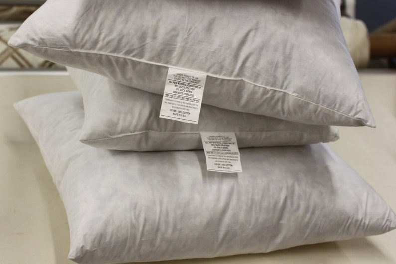 Puede incluir: Tres almohadas blancas apiladas una encima de la otra. La almohada superior tiene una etiqueta blanca con texto negro que dice "All Natural Down Comforter, 100% Duck Down, Fill Weight 20 oz, 100% Cotton Shell, Made in USA". La almohada del medio tiene una etiqueta blanca con texto negro que dice "All Natural Down Comforter, 100% Duck Down, Fill Weight 20 oz, 100% Cotton Shell, Made in USA". La almohada inferior tiene una etiqueta blanca con texto negro que dice "All Natural Down Comforter, 100% Duck Down, Fill Weight 20 oz, 100% Cotton Shell, Made in USA".