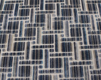May include: Close-up of a fabric with a geometric pattern. The design features rectangular shapes in shades of blue, gray, and white, creating a textured, woven appearance. The pattern is repeated across the fabric.