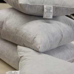 Puede incluir: Tres almohadas blancas de plum&oacute;n apiladas una encima de la otra. La almohada superior tiene una etiqueta blanca con texto negro que dice "All New Natural Contents of this Pillow Except the Cover 80% Duck Feather 20% Duck Down Contents Sterilized Made in USA".