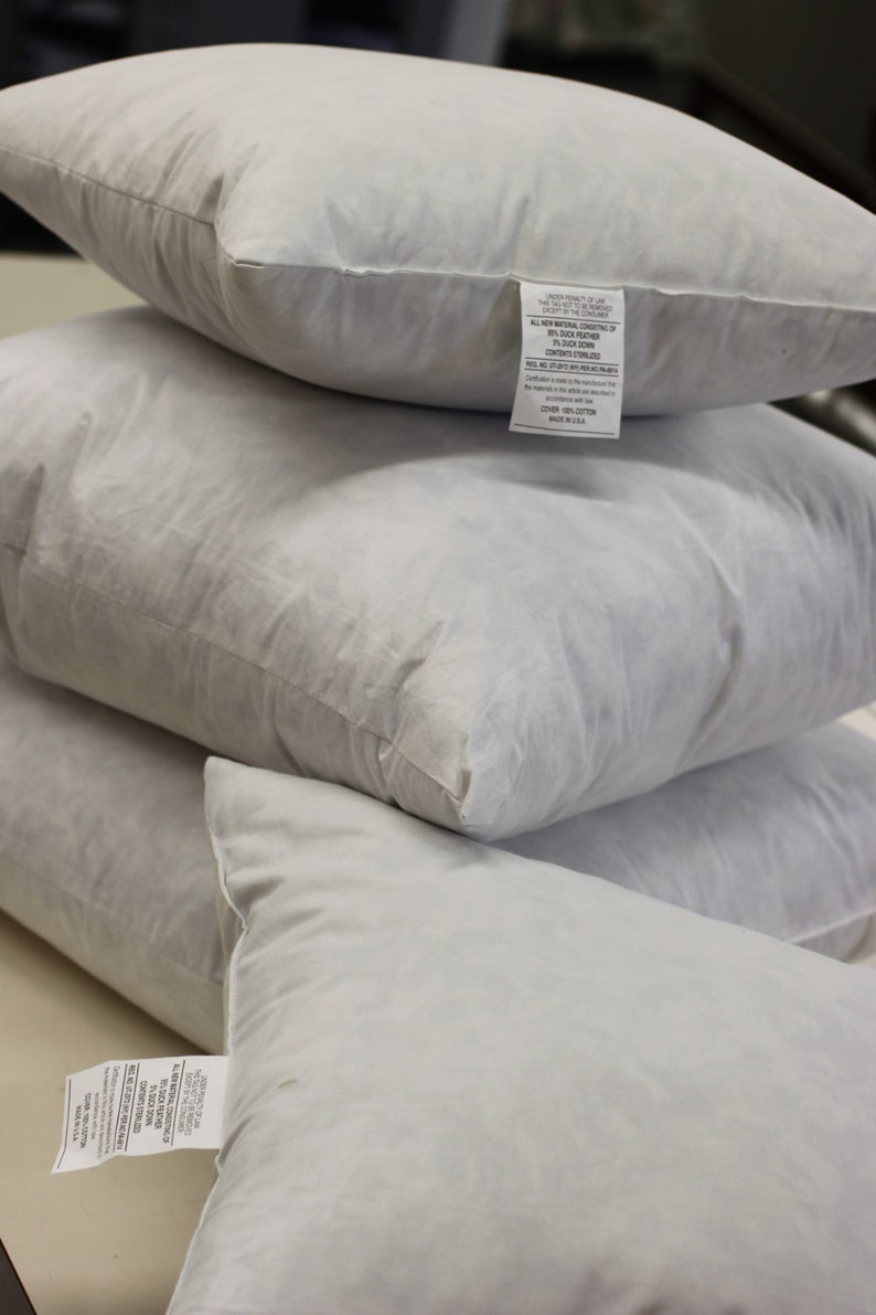 Puede incluir: Tres almohadas blancas de plum&oacute;n apiladas una encima de la otra. La almohada superior tiene una etiqueta blanca con texto negro que dice "All New Natural Contents of this Pillow Except the Cover 80% Duck Feather 20% Duck Down Contents Sterilized Made in USA".
