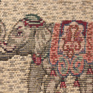 May include: Close-up of a tapestry featuring a detailed woven design of two elephants in shades of red, blue, green, and brown.