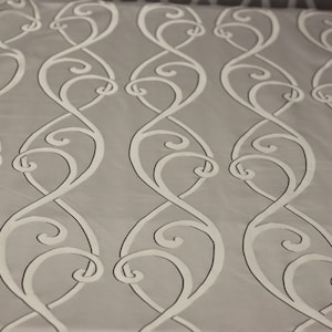 May include: White fabric with a repeating pattern of gray, stylized, swirling lines.