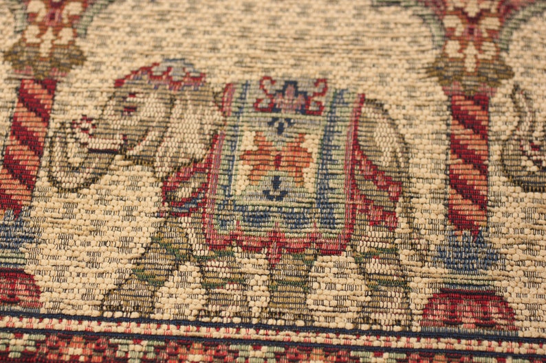 May include: A beige woven rug featuring a colourful elephant design. The elephant is outlined in blue and has a red, orange and green patterned saddle. The rug has a red, blue and green border.
