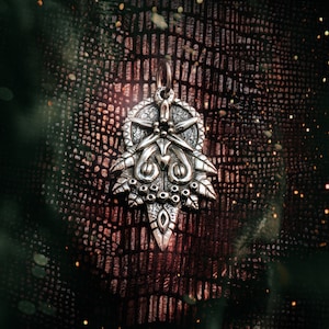 May include: A silver pendant with a detailed design featuring a star, a heart, and leaves. The pendant is on a dark brown textured background.