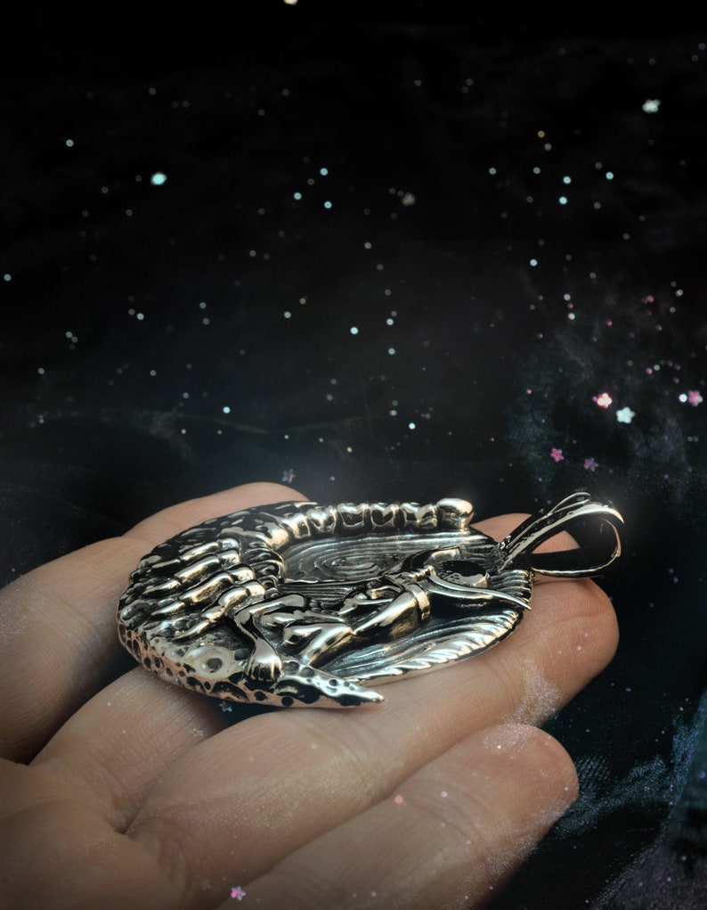 May include: A silver pendant featuring a detailed design of a scorpion curled around a crescent moon.