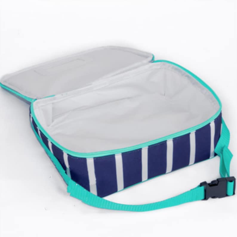 May include: A rectangular lunch bag with a navy blue and white vertical striped pattern. The bag features a bright turquoise zipper trim and an adjustable turquoise strap with a black plastic buckle. The interior is lined with white material.