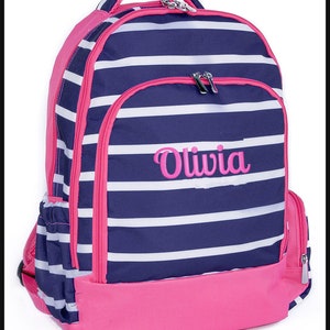 May include: A blue and pink striped backpack with a zippered front pocket and a pink bottom. The backpack has the name "Olivia" embroidered on the front in pink.