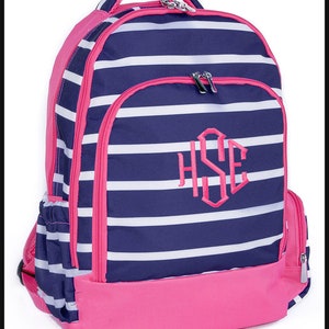 May include: A pink and navy blue striped backpack with white stripes. The backpack has a pink base and trim, with a monogram in the center. It features multiple zippered compartments and a top handle.