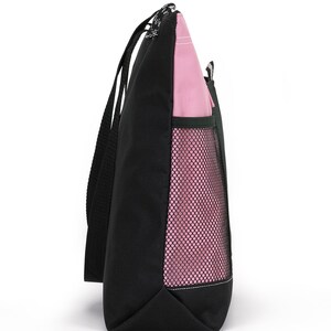 May include: A black and pink tote bag with a mesh pocket on the side. The bag has two long handles.