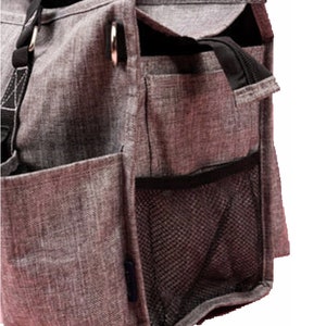 May include: A gray tote bag with multiple pockets and a black strap. The bag has a zippered top and a mesh side pocket. The material has a textured appearance. The bag is designed for carrying items.