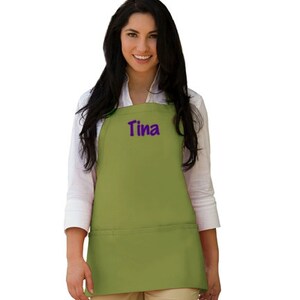 May include: A green apron with a large pocket and the name "Tina" embroidered in purple on the front.
