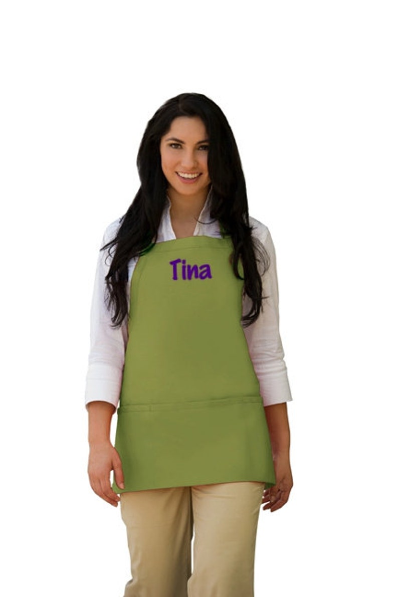 May include: A green apron with a large pocket and the name "Tina" embroidered in purple on the front.