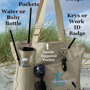 May include: Beige tote bag with multiple pockets, including a large outside pocket, cell phone pockets, and an inside zippered pocket. The bag has adjustable straps and a key or badge holder. The bag is monogrammed with the letter "E" and the word "edwards".