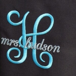 Pu&ograve; includere: Un monogramma ricamato della lettera "H" in blu con il testo "mrs hudson" in grigio sotto.