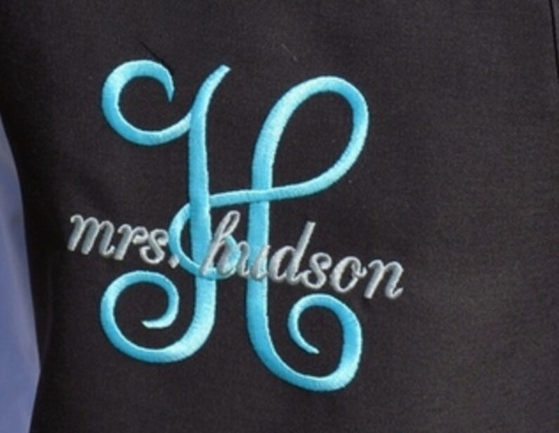 Pu&ograve; includere: Un monogramma ricamato della lettera "H" in blu con il testo "mrs hudson" in grigio sotto.