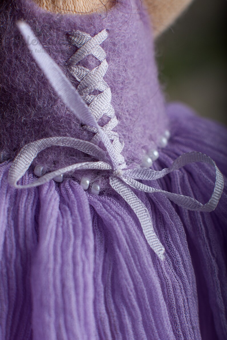 May include: A purple dress with a white lace-up back and a tulle skirt. The dress is decorated with white beads.
