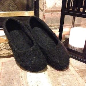 May include: A pair of black knitted slippers with a soft, fuzzy texture.