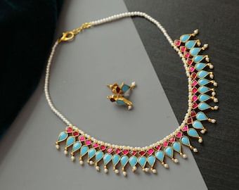 May include: A necklace and matching earring set featuring a strand of small white pearls. The necklace is adorned with alternating teardrop-shaped turquoise and magenta stones set in gold-toned metal, with tiny white pearls dangling from each stone.