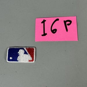 May include: A rectangular patch featuring the MLB logo, with a batter silhouette in white, set against a blue background on the left and red on the right. A pink sticky note with the text "16P" is also present.