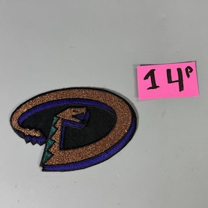 May include: Embroidered patch featuring the Arizona Diamondbacks logo. The logo is an oval shape with a black center, a copper-colored glitter border, and a purple outline. The logo includes a stylized snake and the letter "D".
