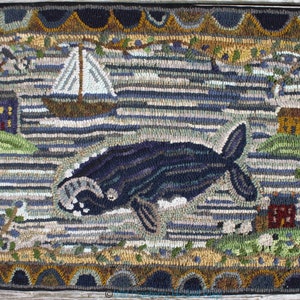 May include: A colorful hooked rug depicting a whale swimming in the ocean. The rug features a sailboat, houses, and other details in a whimsical style.
