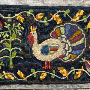 May include: A hooked rug depicting a white turkey with a crown on its head, surrounded by a dark blue background with green vines and yellow leaves. The turkey is standing on a brown ground with red feet.
