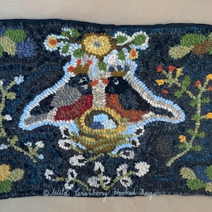 May include: A hand-hooked rug featuring two birds in a nest with a floral design. The rug is on a dark blue background with yellow, red, and green accents. The text "Wild Cranberry Hooked Rugs" is in the bottom right corner.
