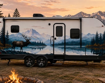 May include: A white travel trailer featuring a large graphic mural of a majestic elk standing near a calm lake with pine trees and snow-capped mountains in the background. The trailer has black wheels, a side door, and two windows on the side.
