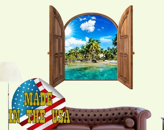 Op de afbeelding: Een 3D-wanddecoratie die een open deur met uitzicht op een tropisch strand laat zien. De sticker heeft een blauwe lucht, witte wolken, palmbomen en turquoise water. De sticker is gemaakt in de VS.