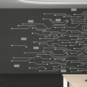 May include: A dark gray wall with a white circuit board design. The design features lines, circles, and arrows. The wall is in an office setting with a desk and a lamp in the foreground.