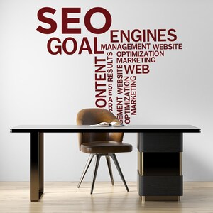Pode incluir: Um ambiente de escritório moderno com uma mesa preta, uma cadeira de couro marrom e um decalque de parede que diz "SEO GOAL" com termos relacionados. O quarto tem um design minimalista com luz natural e pisos de madeira.