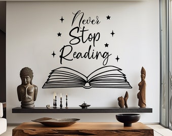 Puede incluir: Una calcomanía de pared en blanco y negro con el texto "Never Stop Reading" y un libro abierto con estrellas alrededor del texto. La calcomanía está en una pared blanca sobre una mesa de café de madera con un tazón encima.